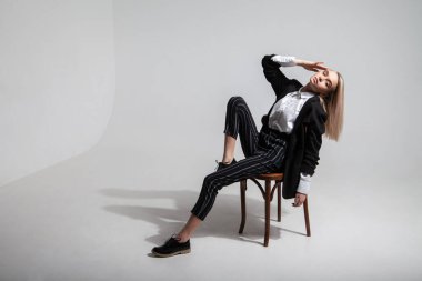 Şık elbiseli kadın sandalyede oturuyor.