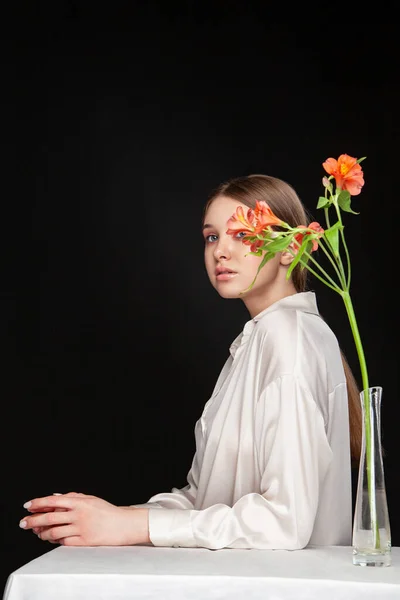 Mujer joven escondiendo la cara detrás de flores frescas — Foto de Stock