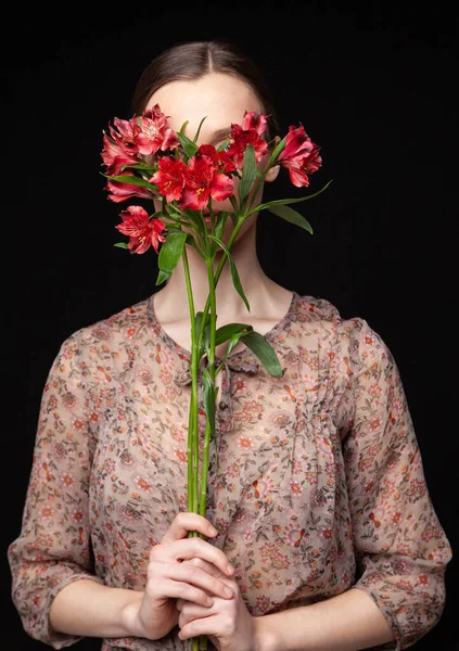 Jovem mulher escondendo rosto atrás de flores frescas — Fotografia de Stock