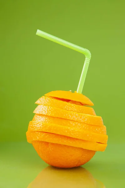 Couper l'orange avec de la paille sur fond vert — Photo