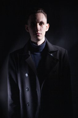 Karanlık stüdyoda siyah ceketli şık bir adam.
