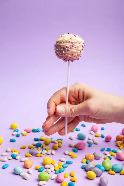 Gewas persoon met cake pop over snoepjes — Stockfoto