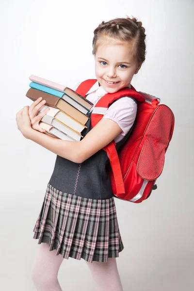 Glückliches kleines Schulmädchen in Uniform steht auf weißem Hintergrund — Stockfoto