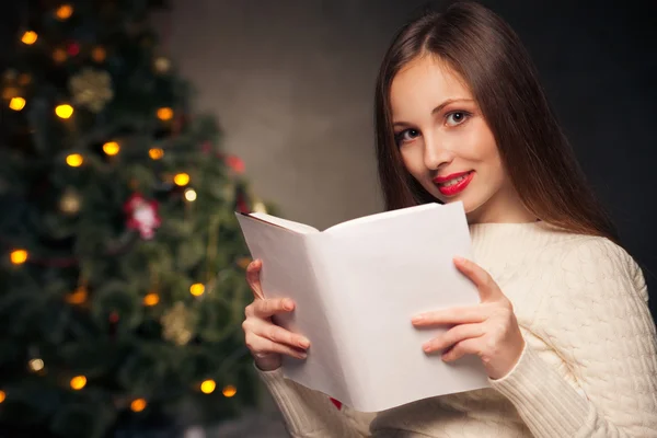 Woman in front of Christmas tree reading book — Stock Photo, Image