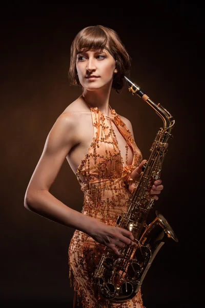 Sexual young woman posing with saxophone at studio — Stock Photo, Image