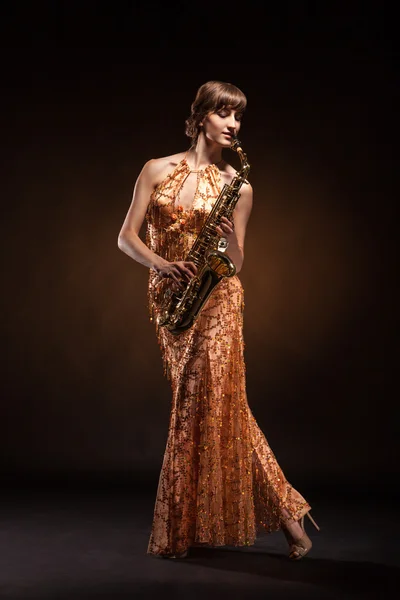 Sexual young woman posing with saxophone at studio — Stock Photo, Image