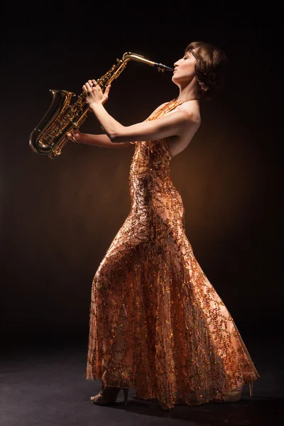 Sexual young woman posing with saxophone at studio — Stock Photo, Image