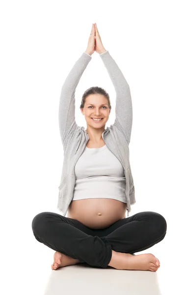 Беременная женщина расслабляется занимаясь йогой над белым — стоковое фото
