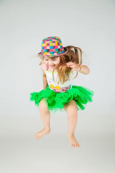 Meisje in groene jurk en hoed springt op wit — Stockfoto