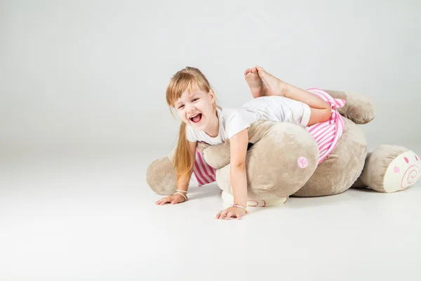 Menina sentada com brinquedo fofinho e sorriso — Fotografia de Stock