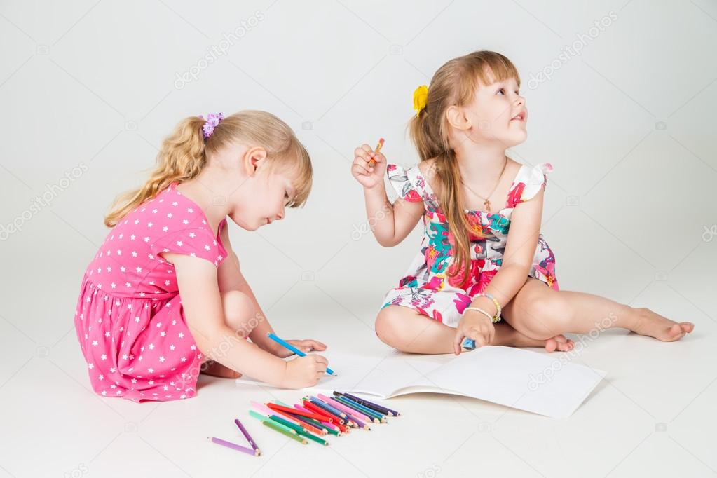 Two lovely girls drawing with colorful pencils