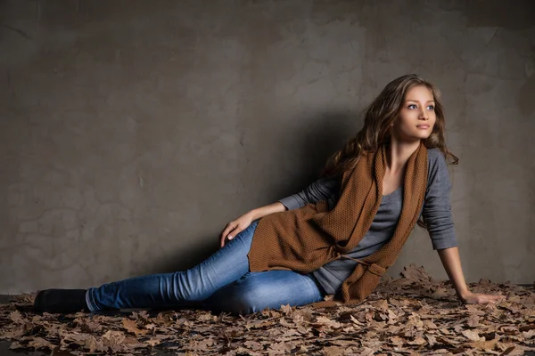 Genç kadın kot pantolon ile sonbahar yaprakları