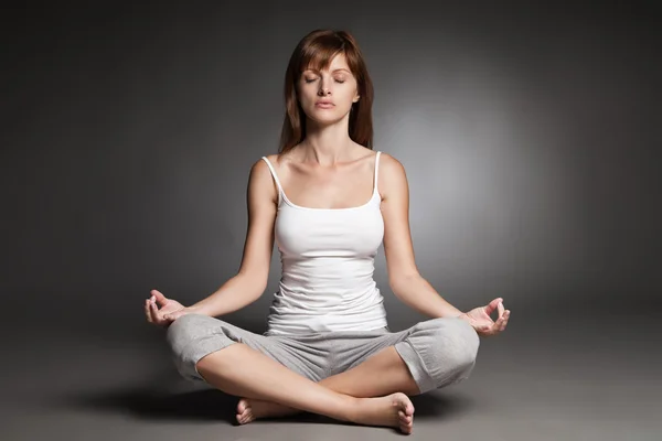 Ung kvinna gör yoga mot mörk bakgrund — Stockfoto