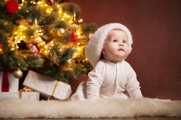 Gelukkig baby dragen KERSTMUTS over kerstboom — Stockfoto