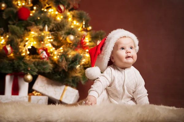 Feliz bebé vistiendo sombrero de Santa sobre el árbol de Navidad —  Fotos de Stock