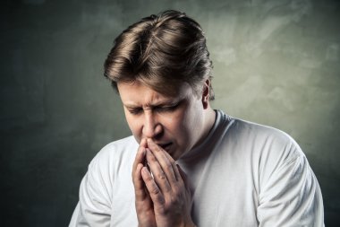 Young man praying on dark background clipart
