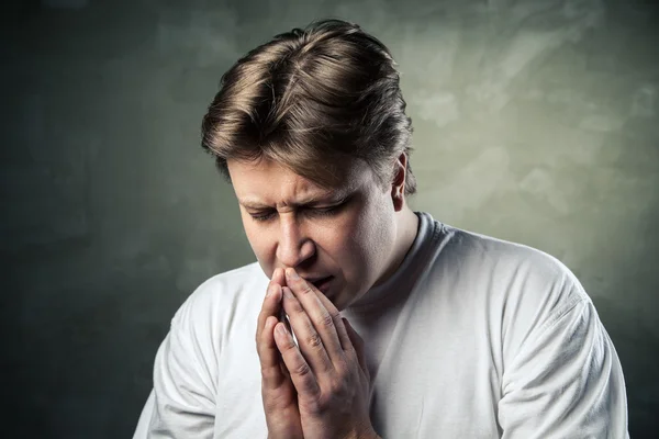 Junger Mann betet auf dunklem Hintergrund — Stockfoto