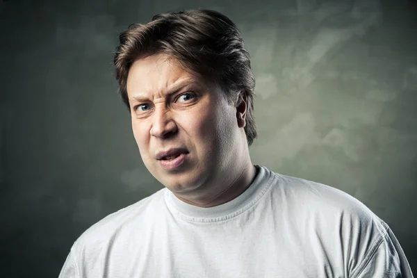 Man with disgusted expression over dark grey — Stock Photo, Image