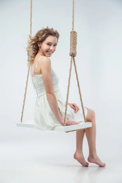 Bella donna sorridente seduta sull'altalena isolata — Foto Stock