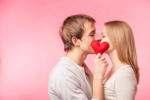 Pareja besándose escondido detrás de poco corazón rojo — Foto de Stock