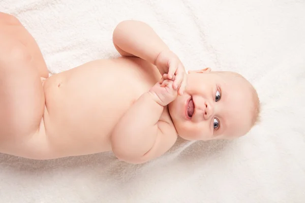 Lindo bebé acostado sobre una manta blanca, manos juntas — Foto de Stock
