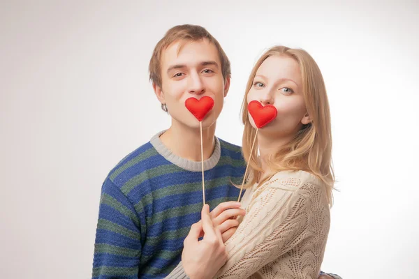 Casal escondendo os lábios atrás de pequenos corações vermelhos — Fotografia de Stock