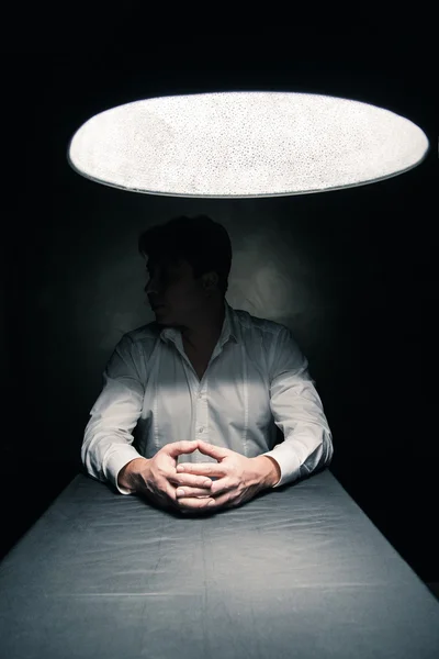 Homem em um quarto escuro iluminado apenas pela lâmpada — Fotografia de Stock