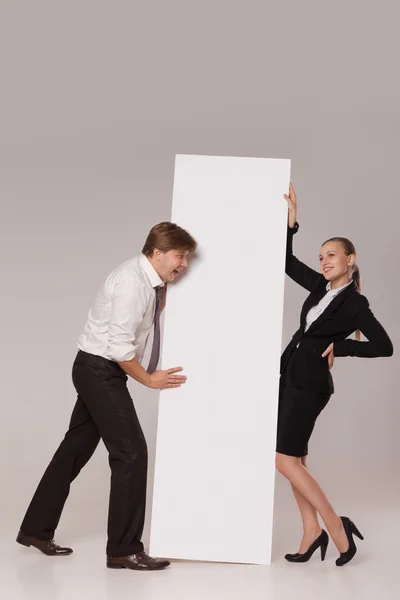 Business man and woman standing over blank banner — Stock Photo, Image