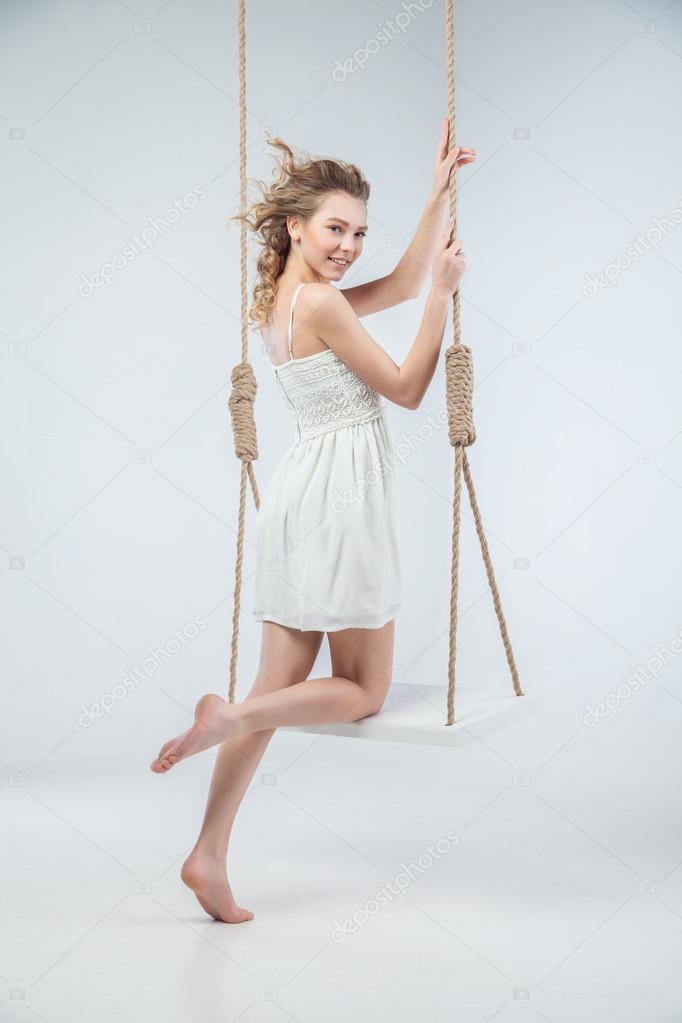 Young bare-footed girl by swing looking in camera