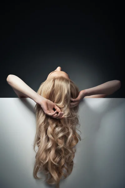 Pretty blond model hiding behind a big sheet of paper — Stock Photo, Image