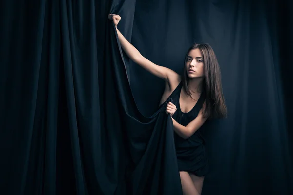 Beautiful fashion model posing and foldinng stage curtains. — Stock Photo, Image