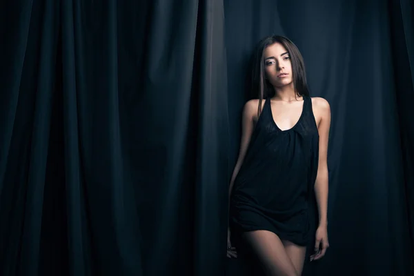 Beautiful fashion model posing in front of stage curtains. — Stock Photo, Image