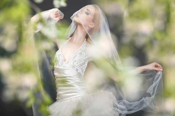 Close up of dreamy beautiful blonde bride walking alone in the park enjoying wind wave and dance