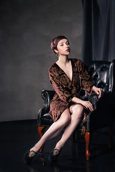 Piękna kobieta sobie krótka sukienka siedząc w fotelu — Zdjęcie stockowe