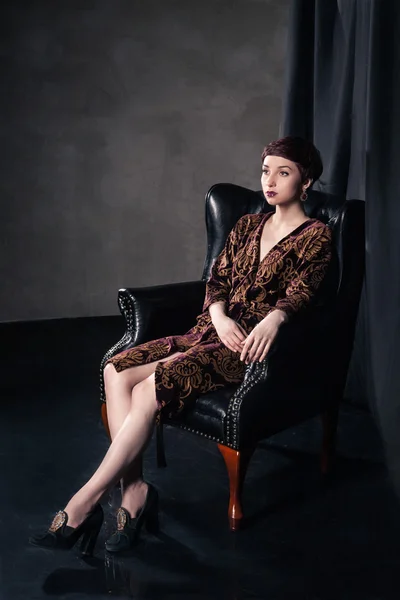 Schöne Frau im kurzen Kleid im Sessel sitzend — Stockfoto