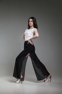 Güzel model gri arka plan üzerinde poz beyaz üst ve siyah etek