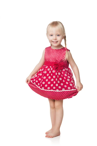 Cute smiling little girl in red dress posing at studio — Stock Photo, Image