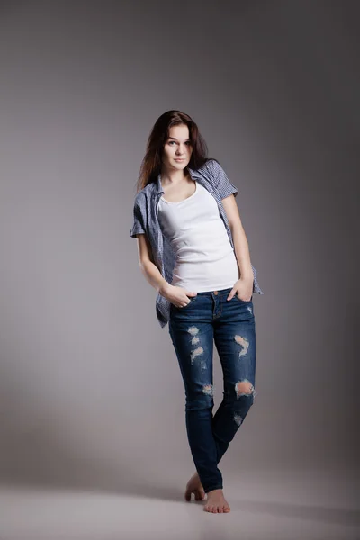 Retrato de uma jovem mulher atraente em roupas de jeans casuais possuindo no estúdio — Fotografia de Stock