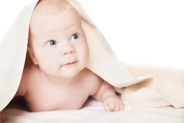 Cute baby under the towel after bathing lies smiling — Stock Photo, Image