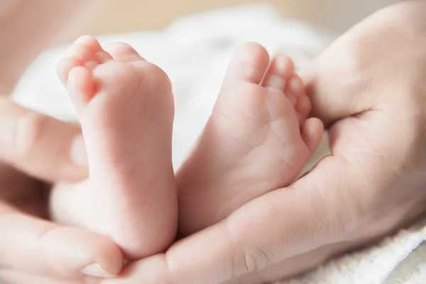 Bovenliggende houden de voeten van zijn pasgeboren babys — Stockfoto