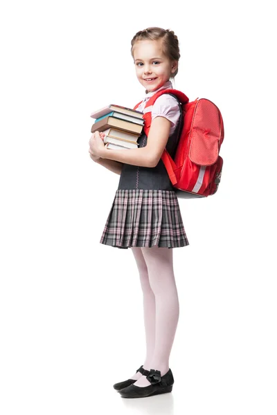 Linda colegiala sonriente en uniforme de pie sobre fondo blanco y sosteniendo libros — Foto de Stock