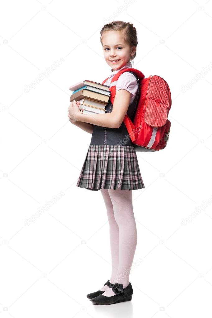 Cute smiling schoolgirl in uniform standing on white background and holding books 