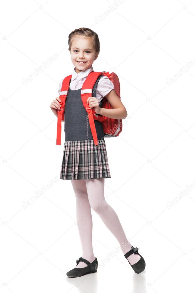 Cute smiling schoolgirl in uniform standing on white background 