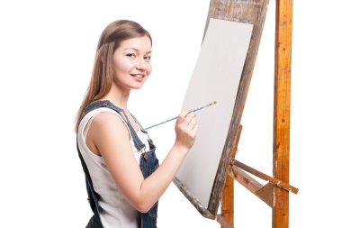 boya fırçası konumu itibariyle şövale olan genç gülümseyen kadın ressam 