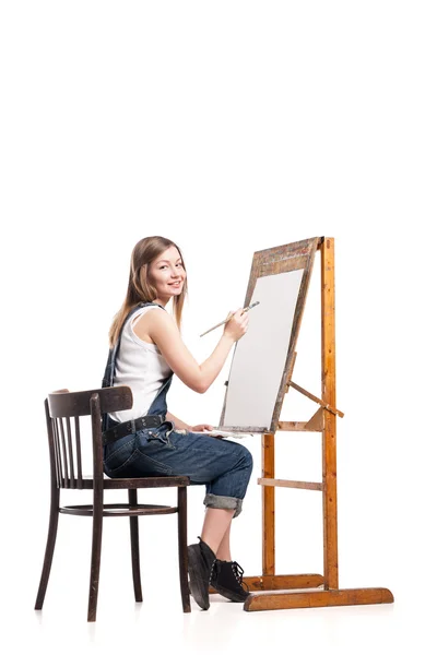 Młody uśmiechający się kobieta malarz z pędzel stojący przy sztalugach — Zdjęcie stockowe