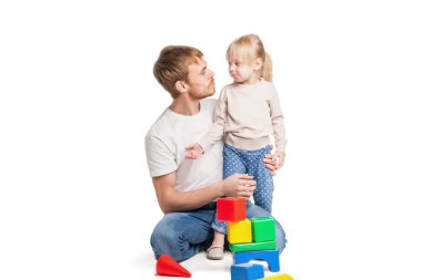 Baby girl building from toy blocks with her father 