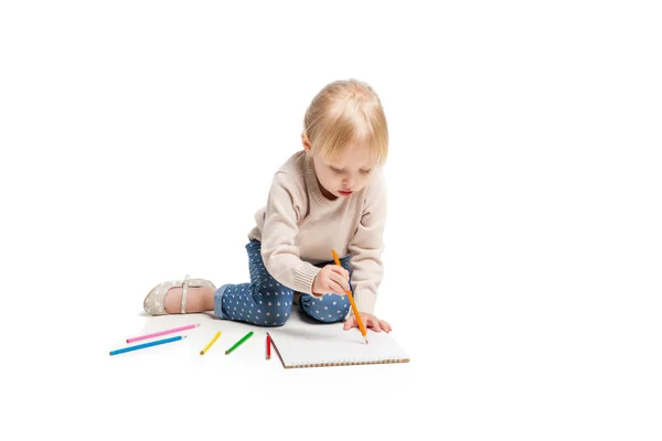 Little cute girl sitting on floor and drawing with colourful pencils — ストック写真