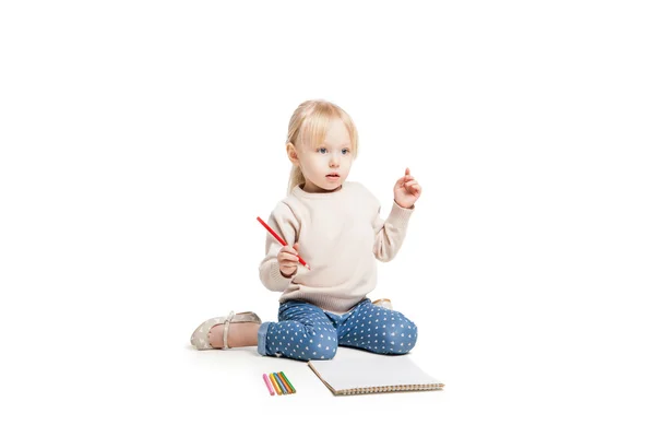 Little cute girl sitting on floor and drawing with colourful pencils — 图库照片