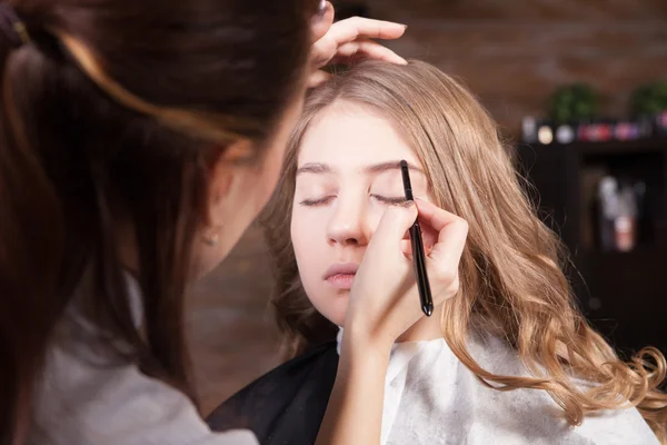 Stylist doing professional make up of young woman — Stock Photo, Image