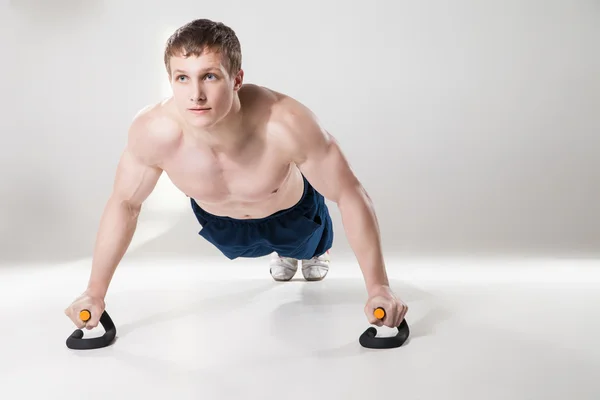 Musculoso deportista sin camisa haciendo flexiones en el estudio — Foto de Stock